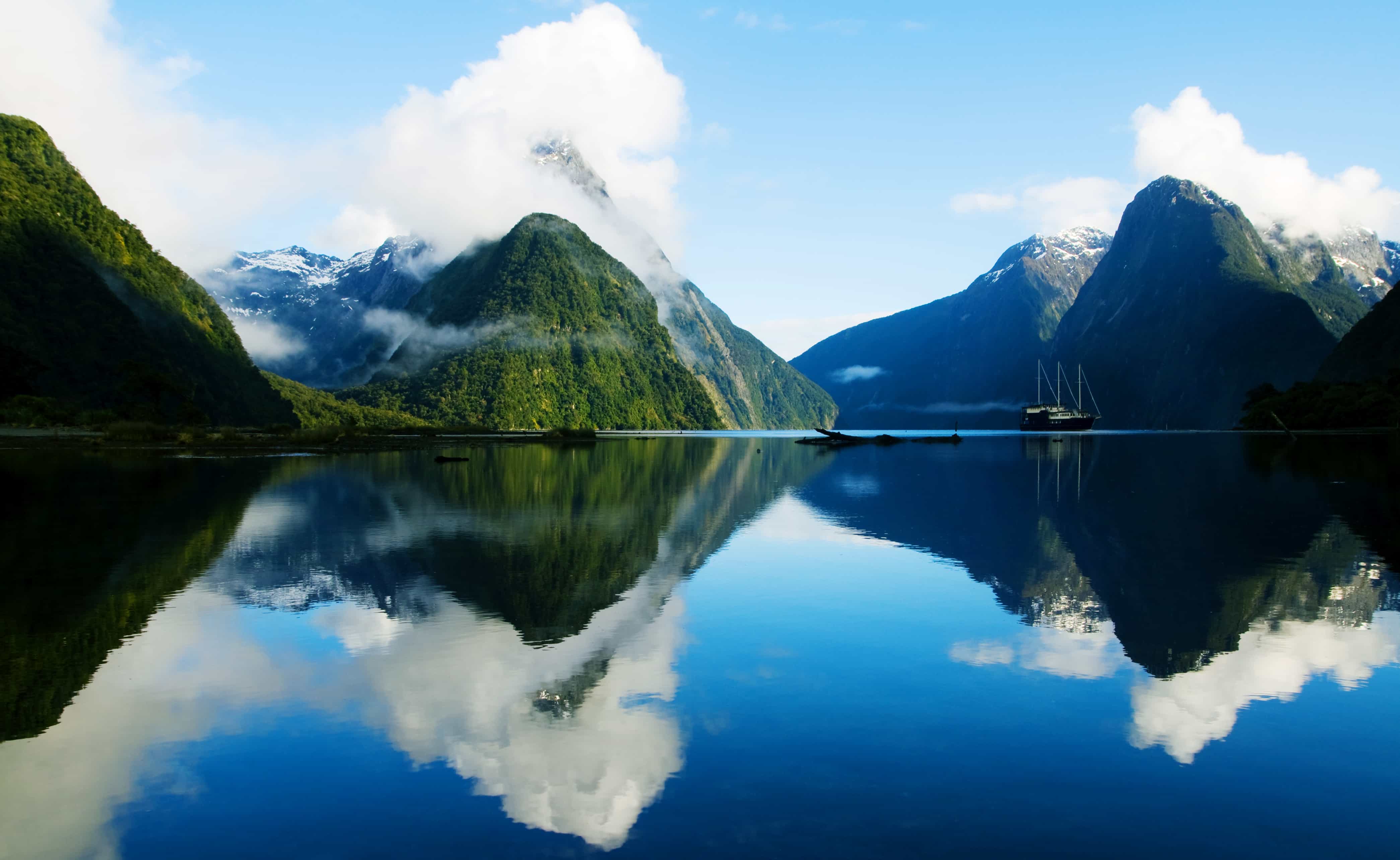 Emerald mountains rising from the glassy waters of New Zealand, a site to behold on your New Zealnd yacht charter